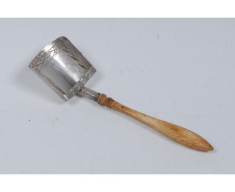 A George III silver tea caddy spoon, the shovel bowl brightly engraved with laureate leaves and wrigglework, turned ivory han