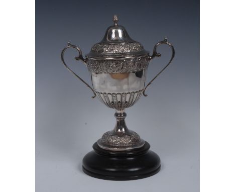 A George V silver half-fluted ovoid pedestal trophy cup, ogee cover with pine cone finial, chased and engraved with bands of 