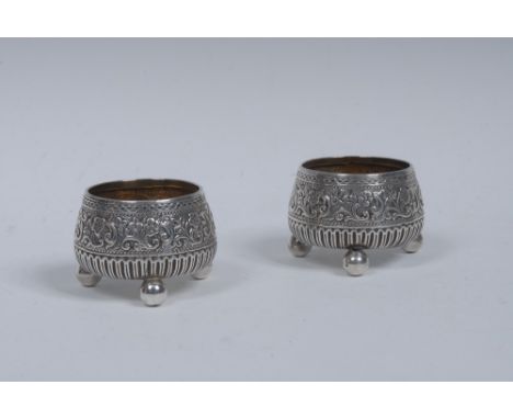 A pair of Victorian silver circular salts, each chased with a band of flowers, cornucopia and scrolling foliage, ball feet, 5