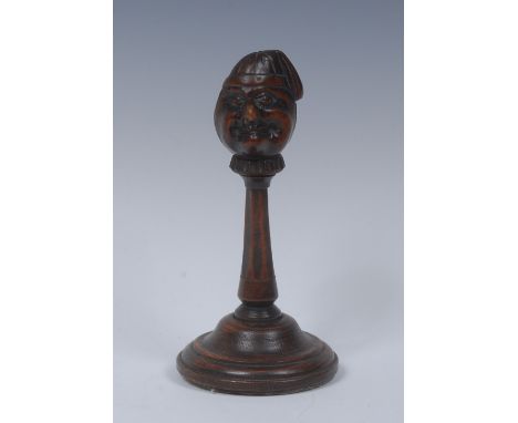 A Black Forest table top novelty screw-action nut cracker, carved as a comical man wearing a night cap, rotating on a turned 