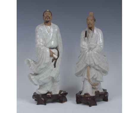 A Chinese stoneware figure of a scholar, standing holding a scroll, crackle glaze, 24cm high;  another, similar, 27cm high (2