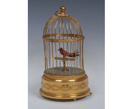 A French clockwork singing bird automaton, domed gilt brass cage with loose ring finial, enclosing a feathered bird on T-shap