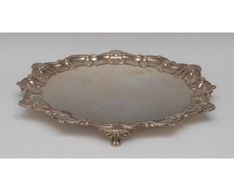 An Edwardian silver shaped circular salver, of 18th century design, fluted shell, C and S-scroll border, plain field, paw fee