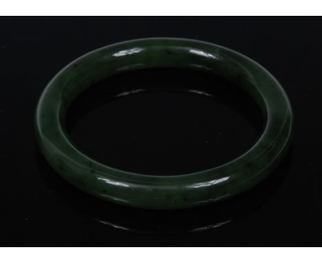 A nephrite jade ring bangle, mottled green body with patchy spotting and clouding throughout, internal diameter 62mm, externa