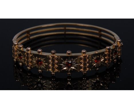 A garnet hinge bangle, top crest inset with five graduated orange/red garnets, each individually mounted within a star cut su