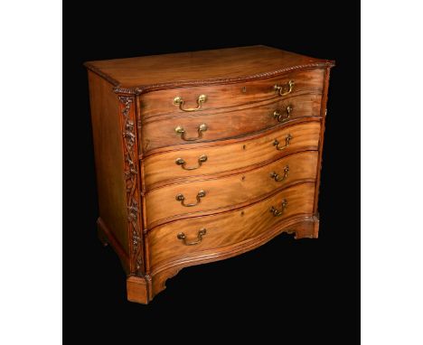 A George III mahogany canted serpentine secretaire chest, oversailing gadrooned top above a fall front drawer fitted with pig