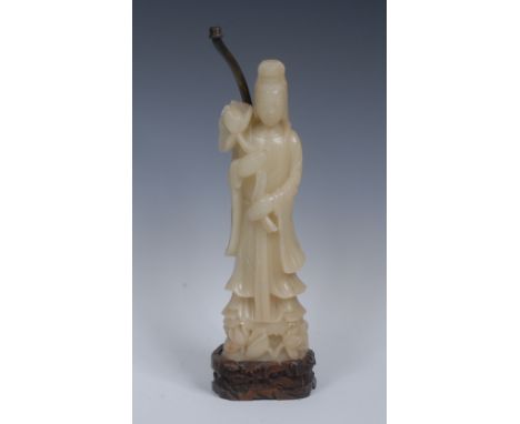 A Chinese soapstone carving, of Guan Yin, she stands, serene, holding a lotus, 32cm high, mounted on a carved hardwood base a