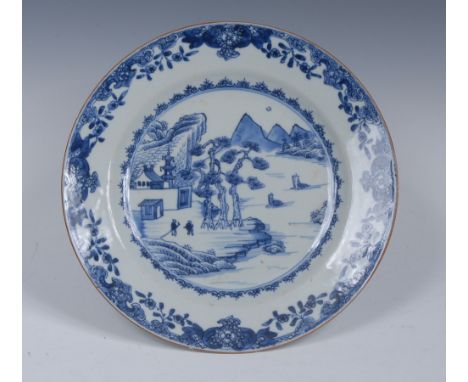 An 18th century Chinese circular plate, pained in underglaze blue with pine trees, mountains, figures and sampans, flower and