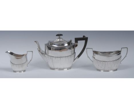 A Victorian silver three piece half fluted oval tea service, comprising teapot, milk jug and sugar basin, hinged cover with k