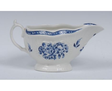 A Worcester sauceboat, painted in underglaze blue with sprays of flowers, moulding with strap flutes and Rococo cartouches, o