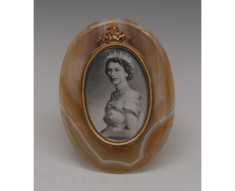 An oval agate frame,  gilt metal bezel ensigned with a love-knot, ivory rear panel, ornate silver strut, containing a photogr