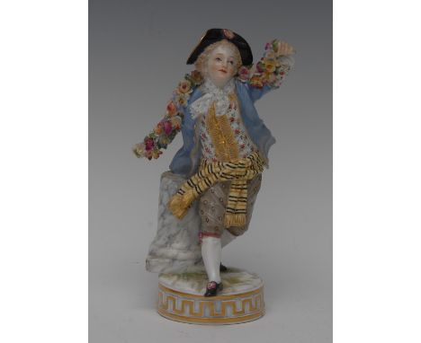 A late 19th century Meissen figure of a boy, he stands with  arms outstretched holding a garland of flowers, wearing a blue j