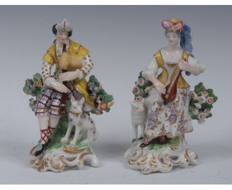 A pair of  Derby Patch Mark figures, of a shepherd and shepherdess, he seated wearing feathered headdress, fanciful dress, do