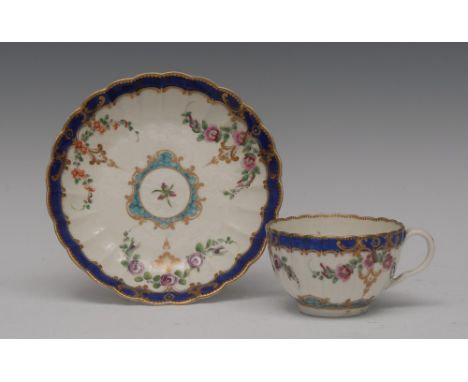 A Worcester fluted teacup and saucer, decorated with trailing flower sprays, Smith's blue banded border with gilt leafy scrol