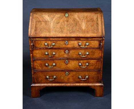 A George II walnut bureau, fall front with book-matched veneer enclosing a cupboard flanked by reeded 'secret' compartments a