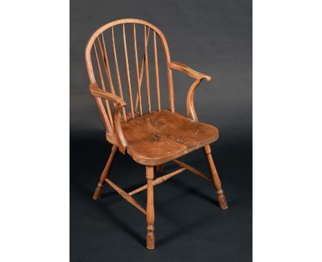 An early 19th century elm Windsor elbow chair, arched stick back, deep saddle seat, turned legs and stretcher, c.1820