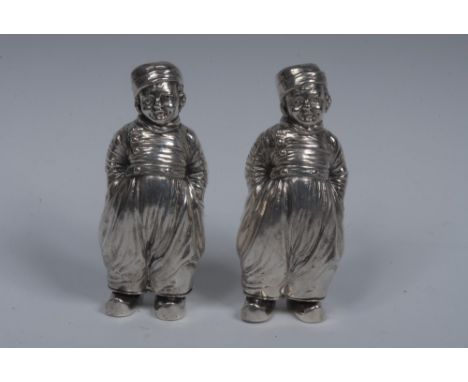 A pair of Elizabeth II cast silver novelty condiments, as Dutch boys, each stands, in traditional dress, his hands in his poc