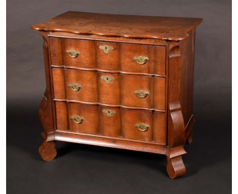 A late 18th century Dutch oak shaped serpentine commode, of small proportions, oversailing top above three long graduated dra