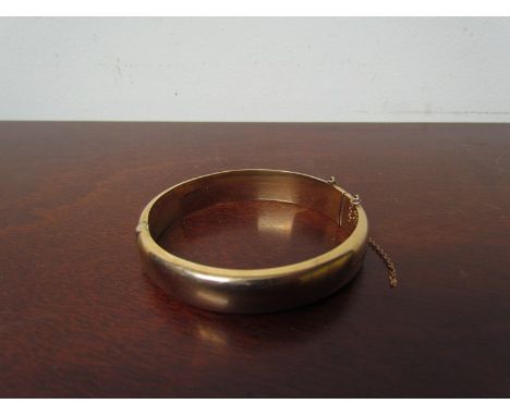A 9ct gold stiff hinge bangle with engraved foliage