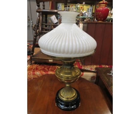 A brass based oil lamp with fluted milk glass shade