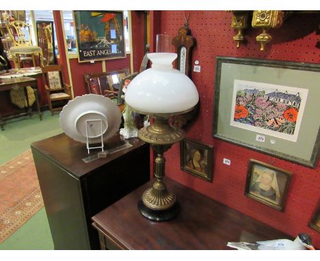 A brass based oil lamp with milk glass shade 