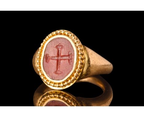 Ca. AD 600.A gold finger ring composed of a D-shaped hoop with expanded shoulders and a large bezel with a beaded border, set