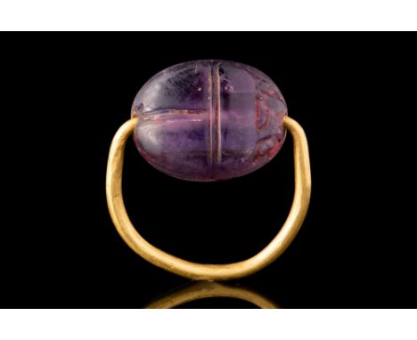 12th Dynasty, Ca. 1820 BC.A gold ring comprised of a thin, D-shaped shank which penetrates a carved amethyst scarab. The scar