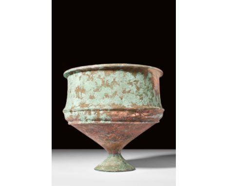 Ca. AD 500.A deep bronze goblet with slightly corseted walls, and a conical-shape base supported by a small, concave foot. Th