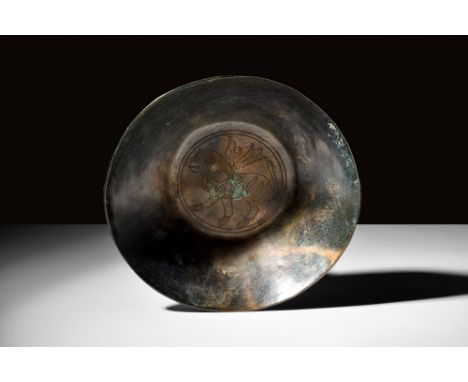 Ca. AD 100-300.A flat-bottomed bronze bowl characterised by its broad profile and smooth walls. It is embellished with a depi