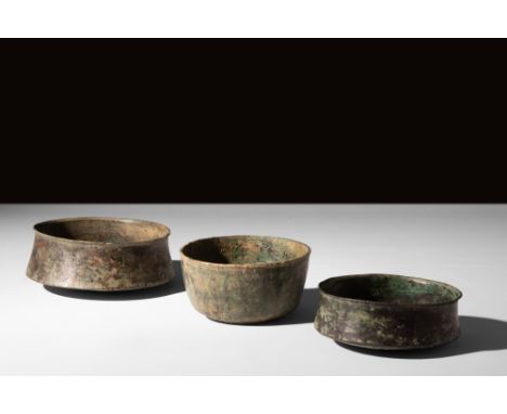 Ca. AD 100-300.A group of three bronze bowls including two shallow bowls, each with a rounded circular base, corseted walls, 