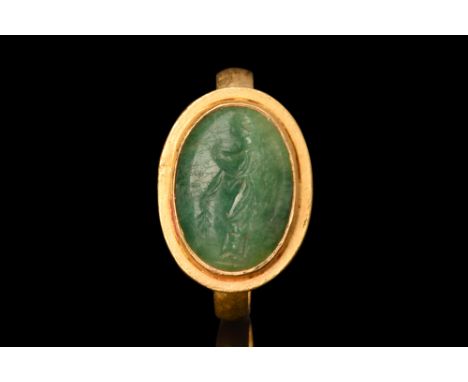 Ca. AD 100-200.A gold finger ring with a slender flat-section band and a sizable bezel set with an emerald intaglio portrayin