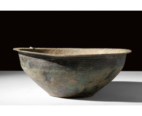 Ca. AD 100-300.A substantial bronze bowl featuring a design that rises from a flat circular base, gradually flaring to an eve