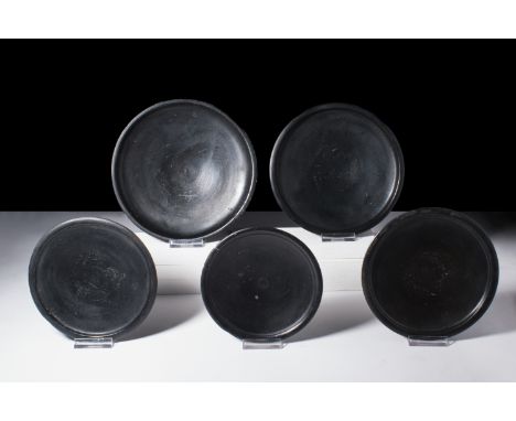 Ca. 400-350 BC. A group of five black-glazed pottery dishes, each with a broad and shallow body that rises gracefully from a 