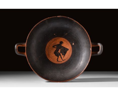 Ca. 500 - 400 BC.A black-figure pottery kylix with a wide cup, upraised opposing handles, all sat upon a short pedestal disc 