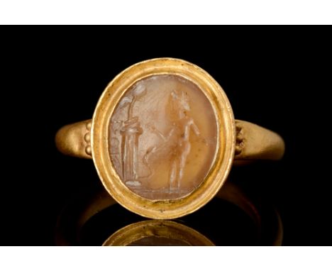 Ca. AD 1-200.A large, oval-shaped jasper or agate intaglio depicting a nude male figure standing in proximity to an altar. A 