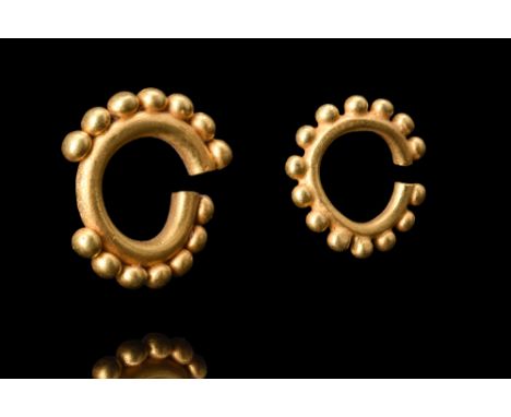 1st millenium BC.A matched pair of gold earrings formed by a round hoop, each adorned with spherical gold beads arranged arou