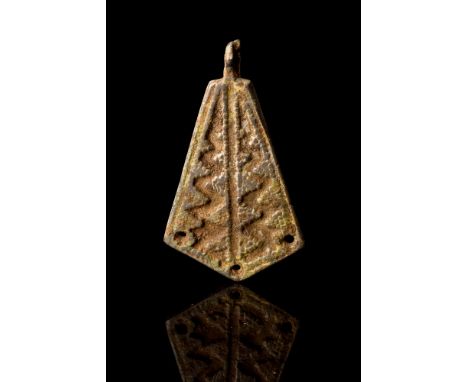 Ca. AD 900-1100.A cast bronze amulet crafted in the form of a dragon's foot, featuring a deltoid-shaped body. The reverse rem