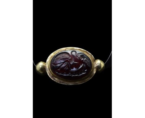 Ca. AD 200.A garnet cabochon intaglio potraying Leda and the Swan, set in a gold pendant flanked by two spheres on each side.