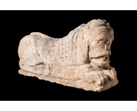 Ca. AD 1000.A stone sculpture depicting a stylised, recumbent lion, resting atop flat base. The lion's legs are neatly folded