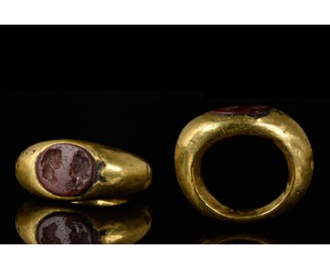 Ca. AD 300-400.A substantial gold ring with hollow hoop widening to the shoulder. The oval bezel is set with a carnelian inta