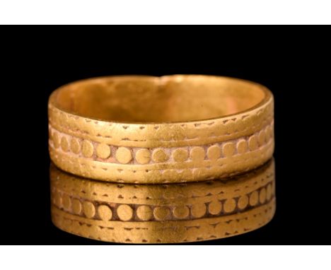 Ca. AD 900-1100.A gold finger band comprising a flat-section hoop with decorative borders and a central register of small cir