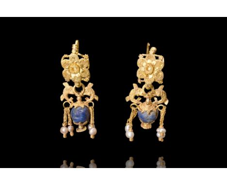 Ca. 4th century BC.A matched pair of earrings, each featuring a hook with a flower-shaped plaque adorned with a dense filigre
