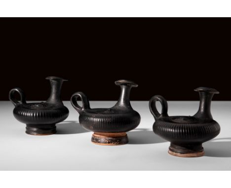 Ca. 4th century BC.A nice group of three terracotta gutti, adorned with a lustrous black glaze. Each vessel features a squat 