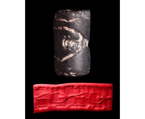 Ca.1800-1600 BC. A black stone cylinder seal depicting a giant figure in a horizontal stance. A wavy border flanks the figure