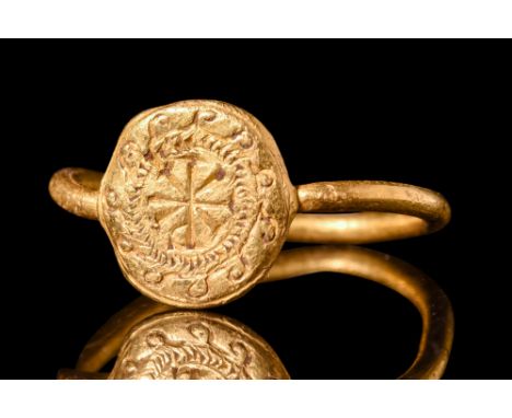 Ca. AD 500.A gold finger ring comprised of a thin, round-section hoop and an applied circular bezel. The flat face of the bez