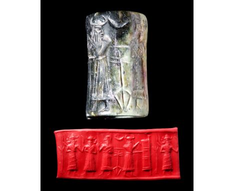 Ca. 2700-2300 BC. A greyish-green specked stone cylinder seal with a large black patch. It depicts four deities with horned c