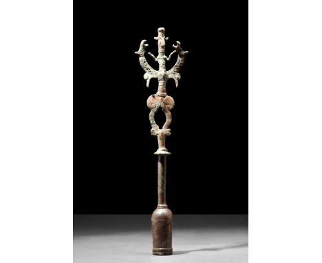 Ca. 1st millennium BC.A bronze sceptre of a janiform design with a highly stylised anthropomorphic figure grasping the long n