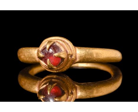 Ca. 8th-11th century AD.A finger ring having a heavy gold round tapered shank with a fine ringed border bezel and four large 