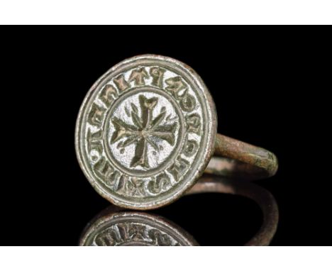 Ca. AD 1100-1400.A bronze seal ring featuring a slender rounded hoop and a large circular bezel adorned with a central cross 