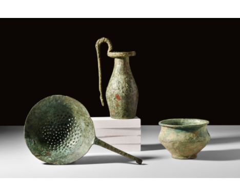 Ca. 500 BC.A group of bronze utensils consisting of a flat-bottomed olpe with a thick rim and a long downfacing handle, a coo